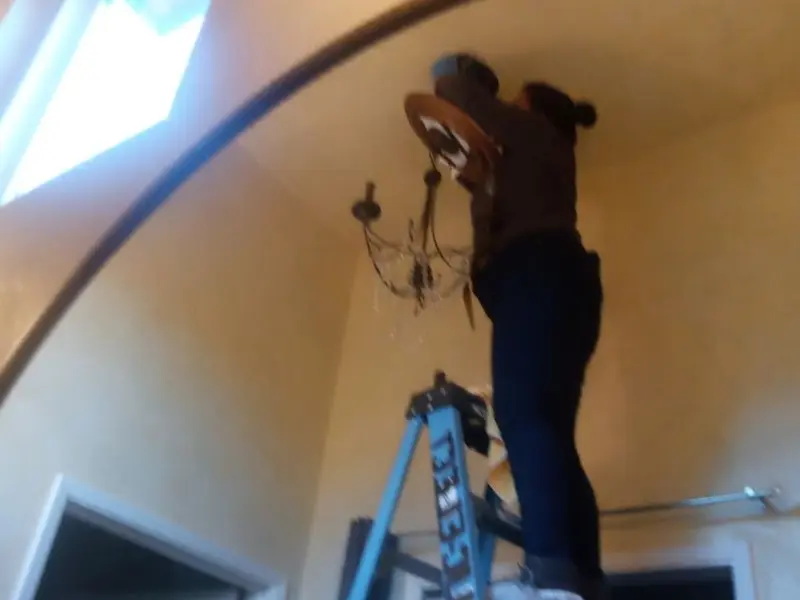 Electrician installing a chandelier in a Hansville residence
